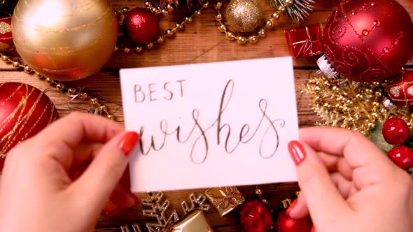 Hands put a card with text BEST WISHES on the table alt