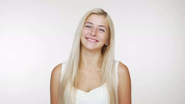Beautiful Blond Lady Smiling Winking Flirting Giving Air Kiss on Camera Over White Background alt