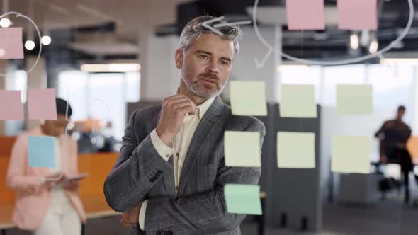 Serious Businessman Manager Examining Information on Sticky Notes and Finding Solution alt