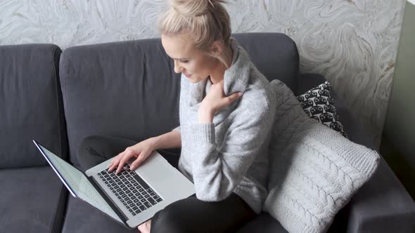 Middle Aged Woman Sitting on Sofa in Her Living Room and Working on Laptop alt