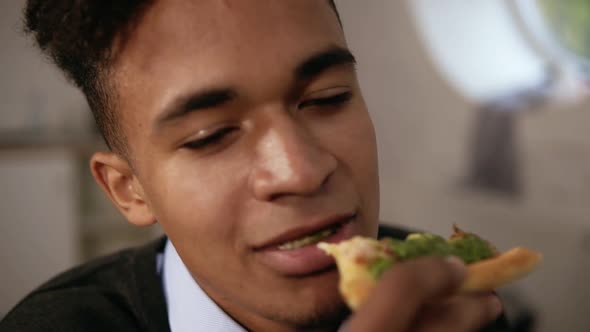 Closeup View of Young African American Enjoying Pizza During Lunch at Work alt