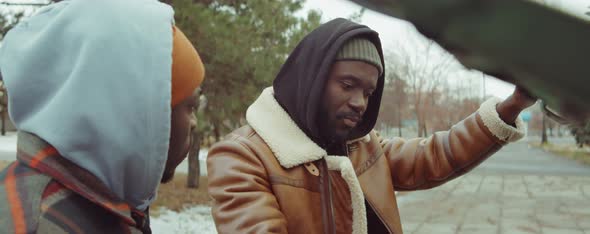 Two African American Men Checking under Car Hood and Speaking alt