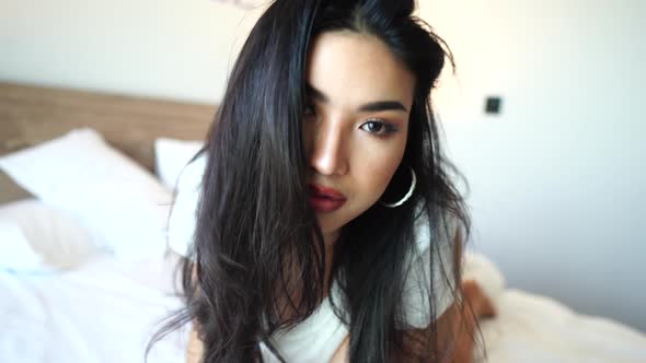 Sexy Asian Woman Posing and Flirting With Camera on Bed Playing With Hair Close alt