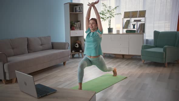 Charming Girl in Sports Uniform Performs Physical Exercises Using Video Busy on Laptop