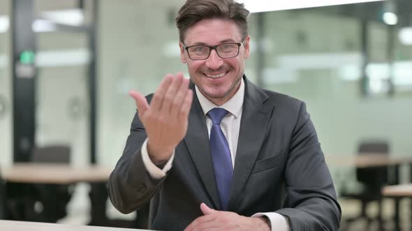 Welcoming Middle Aged Businessman Pointing and Inviting  alt