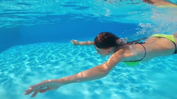 Underwater Shooting. Girl Dive in Blue Swimming Pool.