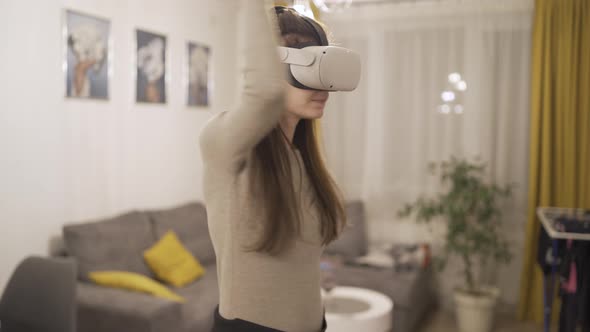 Smiling Girl Having Fun Using Joystick with Headset Goggles Touching Air During Visual Reality alt