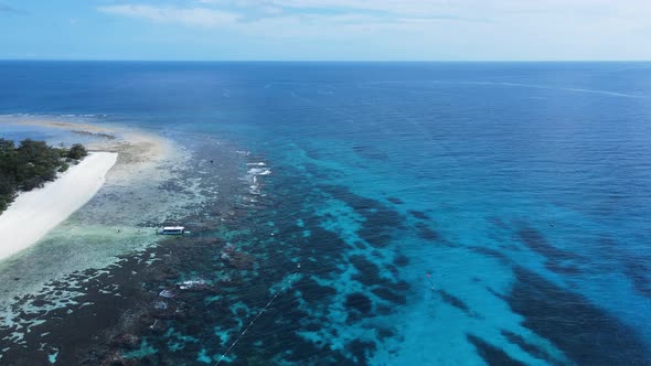 High view across a underwater reef system towards a group of boats moored in the tropical blue Islan alt