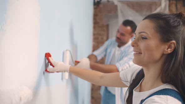 Young Happy Couple Repairing and Painting Wall at Home alt
