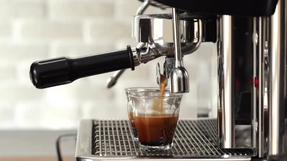 Coffee maker machine brewing double shot Espresso into tumbler glass cups in cafe