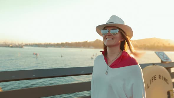 Happy Attractive Woman Walking By Pier, Enjoying Summer Sunset with Water View alt