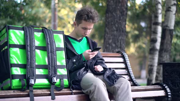 Delivery Man with Green Backpack Awaiting the Order for Delivery alt