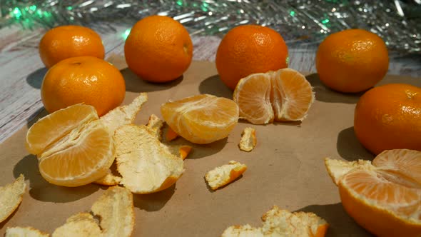 Tangerines and Tangerine Slices on Brown Paper Against the Background of New Year's Lights