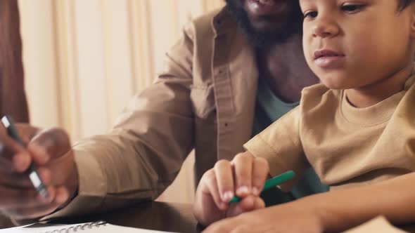 Smiling biracial child drawing with his dad at home