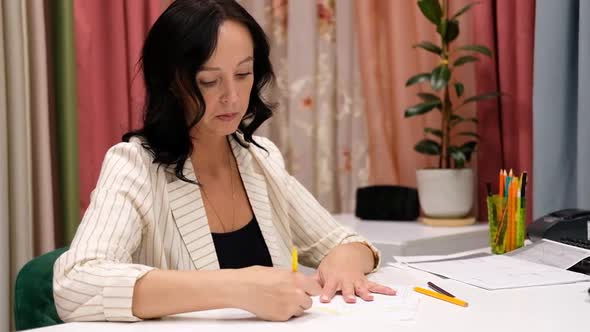 Mature woman designer sketching at fabric store indoor