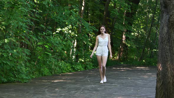 Full length view of young woman walking on park. She is smiling and laughing. Joyful and youth conce alt