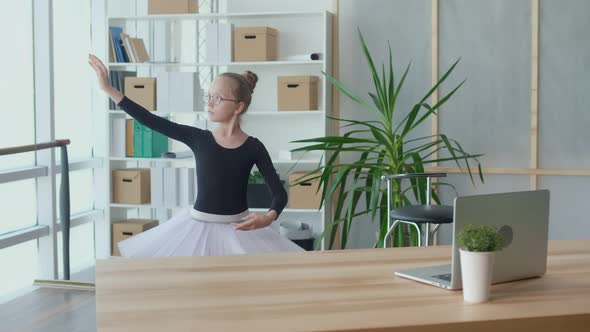 Cute Girl Ballerina Learns the Basics of Rhythmic Gymnastics Using a Laptop alt