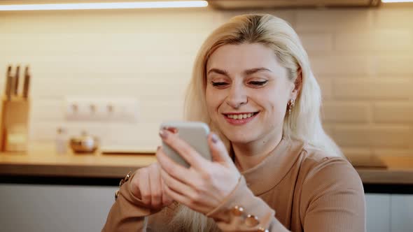 Attractive woman at home using smartphone in kitchen sending message on social media sharing