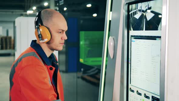 Male Engineer in Headphones is Operating a Computer Console alt