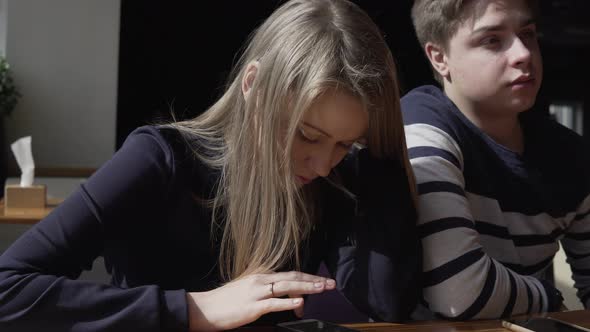 Bored Woman on a Date in Restaurant Ignores Her Date and Concentrates on Her Smartphone alt