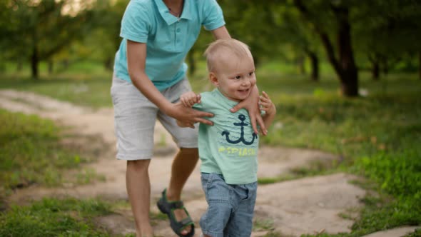 Cute Brothers Walking in Park. Elder Brother Hel Junior To Make Steps Outdoors alt