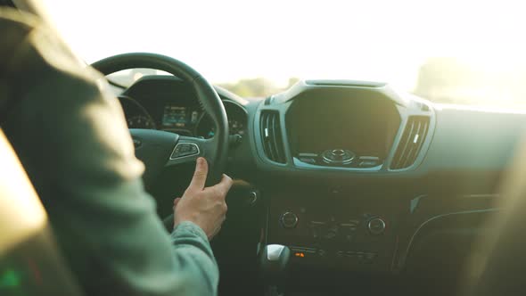 Man Drives a Car Along the Road the Setting Sun Shines in the Windshield alt