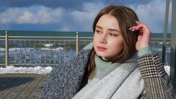 A Woman Wearing a Coat is Sitting on a Swing on the Promenade alt