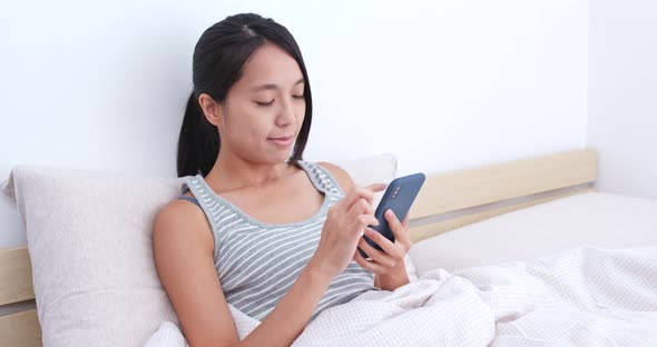 Woman use of mobile phone on bed alt