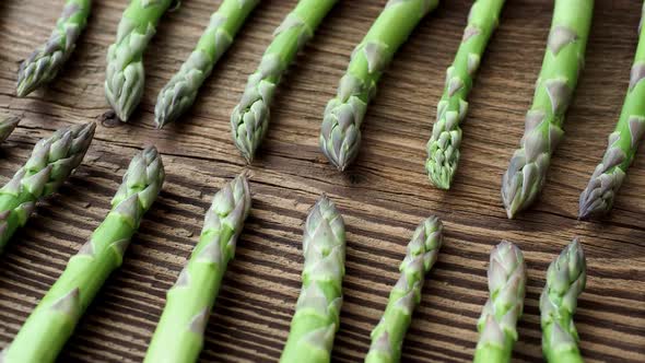 Raw garden asparagus stems. Fresh green spring vegetables on wooden background. 