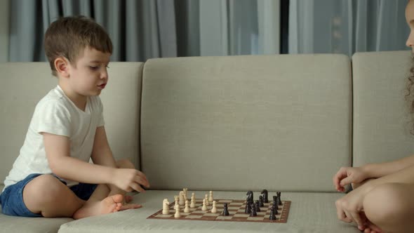 Children Play Chess While Sitting on the Devan at Home the Development of Logical Thinking in alt