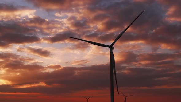 Wind Turbines Generate Power Against Cloudy Sky at Sunset