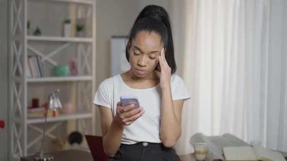 Troubled Young Woman with Migraine Symptoms Messaging on Smartphone Rubbing Temples alt