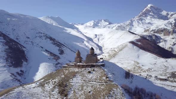 Aerial footage of lonely old Gergeti Trinity Church in winter mountains in Kazbegi, Georgia