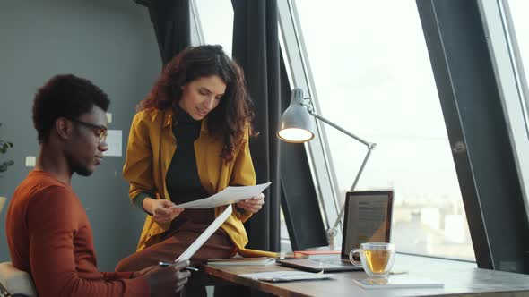 Multiethnic Colleagues Discussing Documents in Office alt