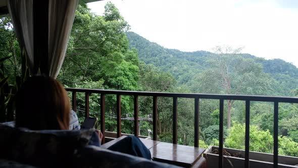 A woman holding and using mobile phone with mountains view