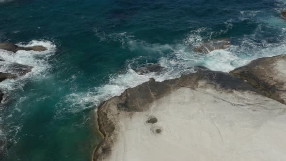 Aerial Birds Eye View of Ocean Waves Crashing on White Rocks in Greece alt