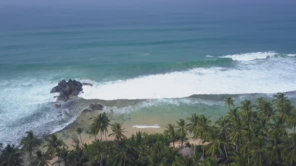 Large Grey Rock Stands Between Sandy Beach and Ocean alt