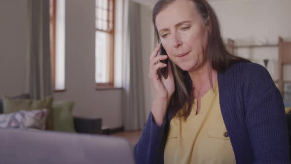 Woman talking on smartphone at home alt