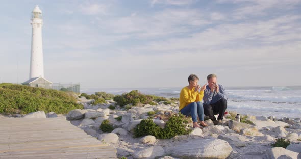 Couple drinking coffee by the sea alt