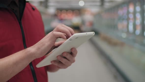 Supermarket Worker Typing On Tablet alt