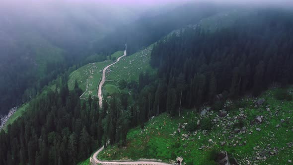Aerial Shot of a Road Diverging Into the Mountains During Monsoon Framed By Clouds in Manali alt