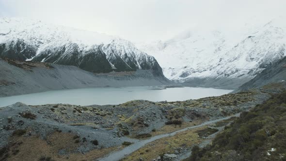 A panning shot of a glacial lake surrounded by snow capped mountains on a cold winters day in New Ze alt