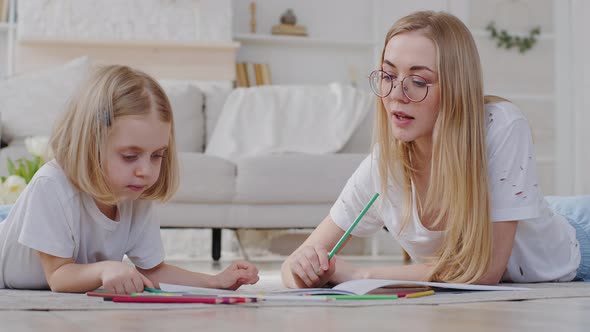 Home Education Mom with Daughter Little Girl Learning to Draw Lying on Living Room Floor Creative alt