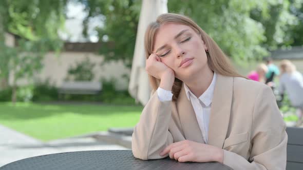 Sleeping Young Businesswoman Sitting in Outdoor Cafe alt