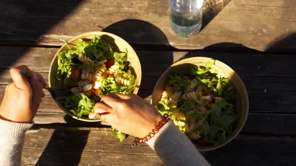 Caucasian woman mixing a mediterranean greek salad with feta cheese on a bamboo bowl in slow motion alt