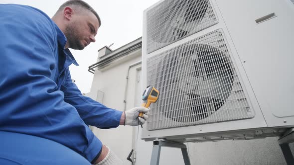 Technician uses a thermal imaging infrared thermometer to check the condensing alt