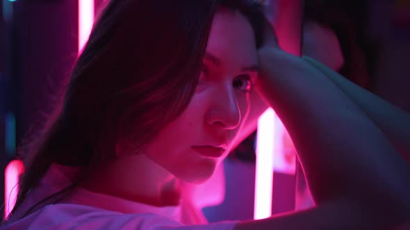 The Colored Bright Pink Lighting on the Face of a Beautiful Young Woman Is Closeup