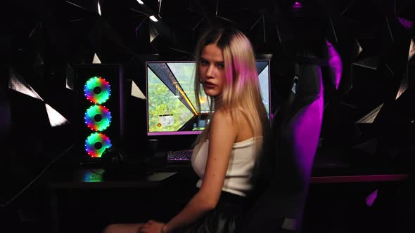 Blonde and Pretty Gamer Girl Turns Away From the PC Monitor and Looking in the Camera in Neon alt