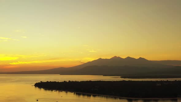Yellow sunset of a small island, a large body of water and mountains in popular holiday location of alt