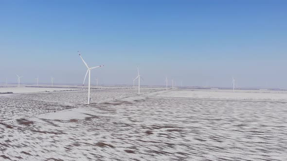 Windmills with Blades Stand in Covered with Snow Field